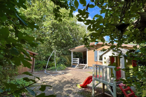 Speelplein en terras bij een klein familiechalet vlak bij het strand in Nederland, groene omgeving.