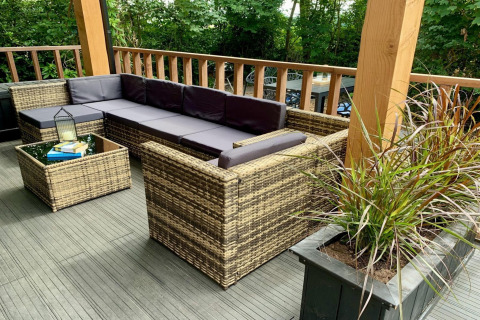 Moderne chalet-terras in Nederland met rotanmeubilair, paarse kussens en groene planten.
