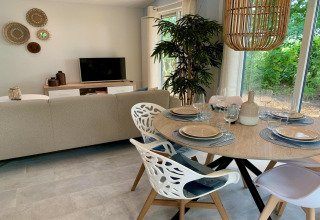 Modern chalet in Nederland met stijlvolle eetkamer, grote ramen en uitzicht op groene natuur buiten.