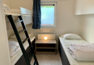 Modern chalet met stapelbed, enkel bed, nachtkastje en raam in Nederland.