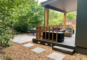 Modern chalet met overdekte veranda en terras, omgeven door bomen in Nederland.