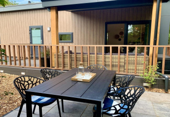 Table à manger extérieure sur la terrasse d’un chalet moderne avec véranda couverte aux Pays-Bas.