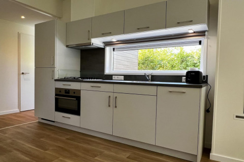 Moderne Küche in einem einzigartigen Chalet in den Niederlanden mit großen Fenstern und Holzfußboden.