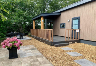 Chalet moderne aux Pays-Bas avec terrasse en bois, véranda couverte, jardin et coin repas extérieur.