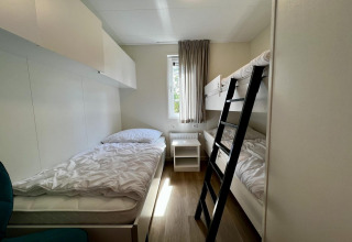 Slaapkamer in Unique chalet voor 5 met eenpersoonsbed, stapelbed, raam en licht gordijn in Nederland.