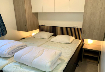 Habitación de chalet moderno en Países Bajos con dos camas individuales, armarios y lámparas.