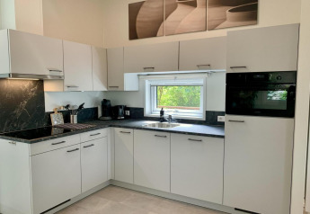 Cuisine moderne avec placards blancs, plan noir, fenêtre et électroménagers dans un chalet aux Pays-Bas.