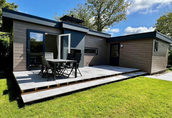 Modernes Chalet für 5 Personen mit Garten, großer Terrasse und Essbereich im Freien bei Sonnenschein.