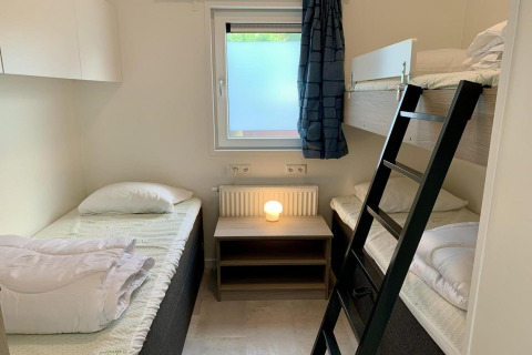 Modernes Chalet-Schlafzimmer mit Etagenbett, Einzelbett, Fenster und Nachttisch in den Niederlanden.