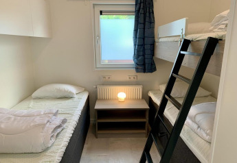 Habitación de chalet moderno con literas, camas individuales, ventana y lámpara en los Países Bajos.