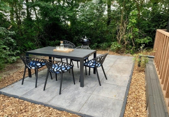 Espace repas extérieur d'un chalet moderne avec terrasse et véranda, entouré de verdure aux Pays-Bas.