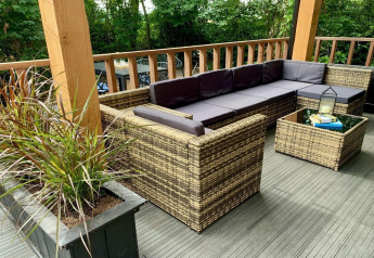 Buiten terras met moderne rotan zitmeubels en planten bij een chalet in Nederland.