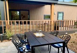 Chalet moderno en los Países Bajos con terraza de madera, veranda y comedor exterior elegante.