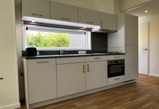 Cucina moderna con armadietti bianchi, forno, ampia finestra in chalet per 5 persone nei Paesi Bassi.