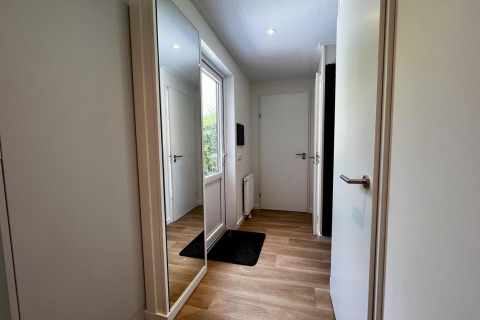 Ingresso di uno chalet unico per 5 persone nei Paesi Bassi con grande specchio e pavimento in legno.