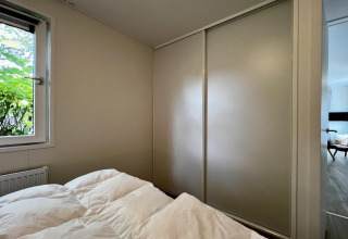 Camera da letto in un lodge con piumone bianco, armadio scorrevole e finestra nei Paesi Bassi.