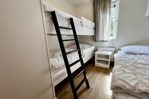 Camera con letto a castello, letto singolo, comodino e finestra al Unique chalet for 5 with garden nei Paesi Bassi.