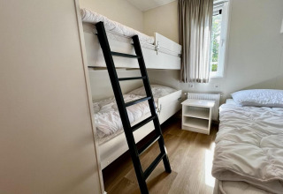 Kamer met stapelbed, eenpersoonsbed, nachtkastje en raam in Unique chalet for 5 with garden in Nederland.