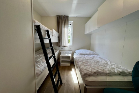 Chambre lumineuse avec lits superposés, lit simple et fenêtre dans un chalet unique pour 5 aux Pays-Bas.