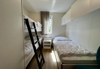 Lichte kamer met stapelbed, eenpersoonsbed, bureau en raam in uniek chalet voor 5 in Nederland.