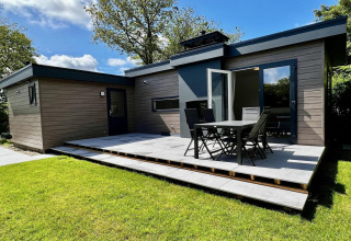 Modern houten chalet voor 5 personen met ruime tuin en terras, gelegen in Nederland onder blauwe lucht.