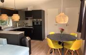 Chalet moderne avec jardin et terrasse, coin repas avec chaises jaunes et cuisine ouverte, aux Pays-Bas.