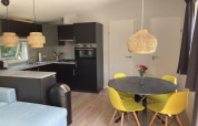 Chalet moderno con giardino e terrazza, tavolo con sedie gialle e cucina aperta, situato nei Paesi Bassi.