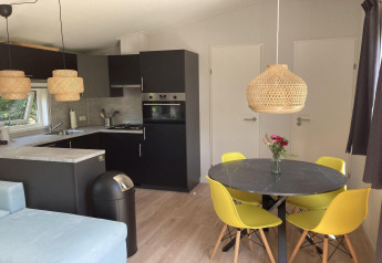 Modernes Chalet mit Garten und Terrasse, Essbereich mit gelben Stühlen und offener Küche in den Niederlanden.