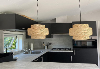 Modernes Chalet-Küche in den Niederlanden mit schwarzen Schränken, runden Lampen und Fenster.