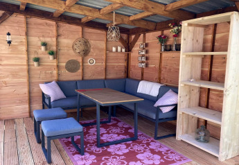 Coin salon confortable dans un chalet moderne avec murs en bois, étagère et coussins décoratifs.
