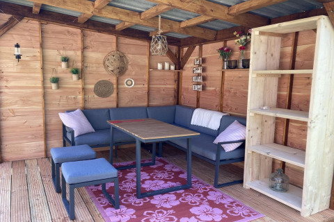 Area lounge accogliente in uno chalet moderno con pareti in legno, scaffale e sedute blu.