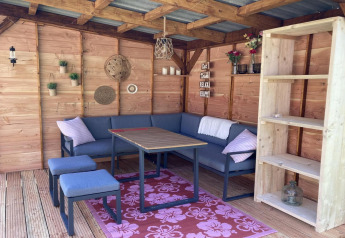 Acogedora zona de estar en chalet moderno con paredes de madera, estantería y detalles decorativos.