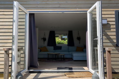 Modern chalet in Nederland met openslaande deuren naar terras en gezellige woonkamer binnen.