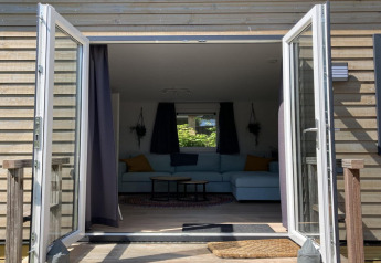 Modern chalet med åbne døre til terrasse og indbydende stue, beliggende i Holland.