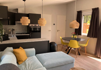 Interno di chalet moderno nei Paesi Bassi con cucina a vista, sedie gialle e tavolo rotondo.