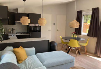 Interno di chalet moderno nei Paesi Bassi con cucina a vista, sedie gialle e tavolo rotondo.