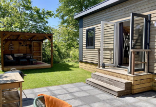 Modern chalet met tuin, terras en open deuren in een zonnige Vlaamse omgeving in Nederland