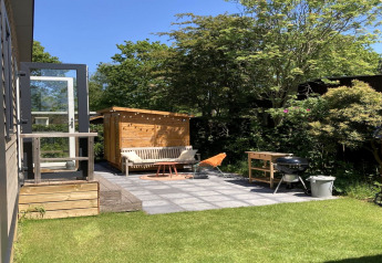 Chalet moderno con giardino e terrazza nei Paesi Bassi, patio soleggiato con barbecue e panchina.