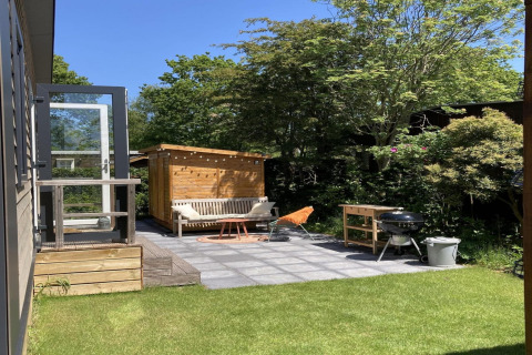 Chalet moderno con giardino e terrazza nei Paesi Bassi, patio soleggiato con barbecue e panchina.