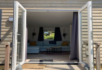 View through open glass doors into the living room of 'Modern chalet with garden, terrace' in the Netherlands.