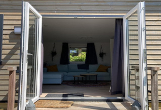 Uitzicht door openstaande glazen deuren naar de woonkamer van 'Modern chalet with garden, terrace' in Nederland.