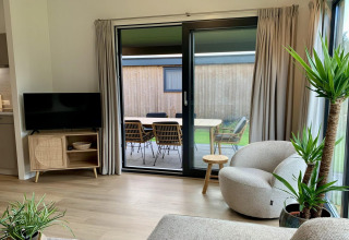 Woonkamer met moderne meubels en groot raam met zicht op terras in Pleasant chalet met veranda, Nederland.