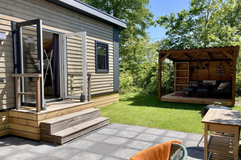 Modernes Chalet mit Garten, Terrasse und überdachtem Loungebereich im sonnigen Holland, gemütlich und einladend.