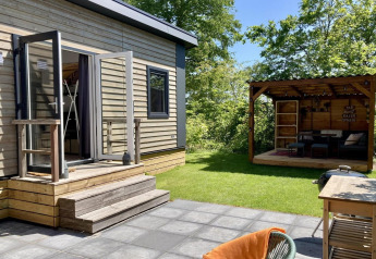 Chalet moderno con giardino, terrazza e zona lounge coperta all'aperto nei Paesi Bassi, giornata soleggiata.