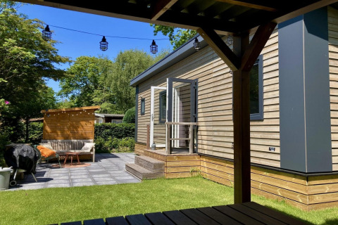 Modernes Chalet mit Garten, Terrasse und Sitzbereich unter einer Pergola in den Niederlanden.