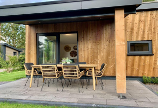 Veranda van het Pleasant chalet in Nederland met houten gevel, buitentafel en acht stoelen.