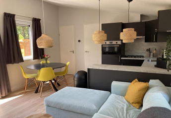 Modernes Chalet in den Niederlanden mit gelben Stühlen, Rattanhängelampen und gemütlicher Sitzecke.