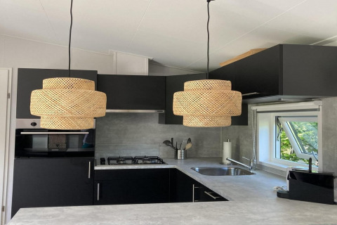 Moderne chaletkeuken in Nederland met donkere kasten, gevlochten hanglampen en raam op de tuin.