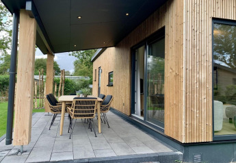 Udendørs terrasse med spisebord og stole ved charmerende træbeklædt chalet i Holland.