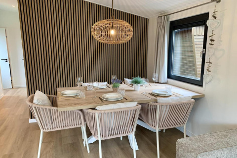 Comedor moderno en 'Pleasant chalet with veranda' en Países Bajos, con muebles claros y lámpara colgante.